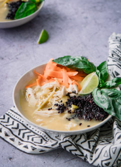 泰国风格的汤配鸡肉和禁忌的黑米饭，罗勒在蓝色桌子上。