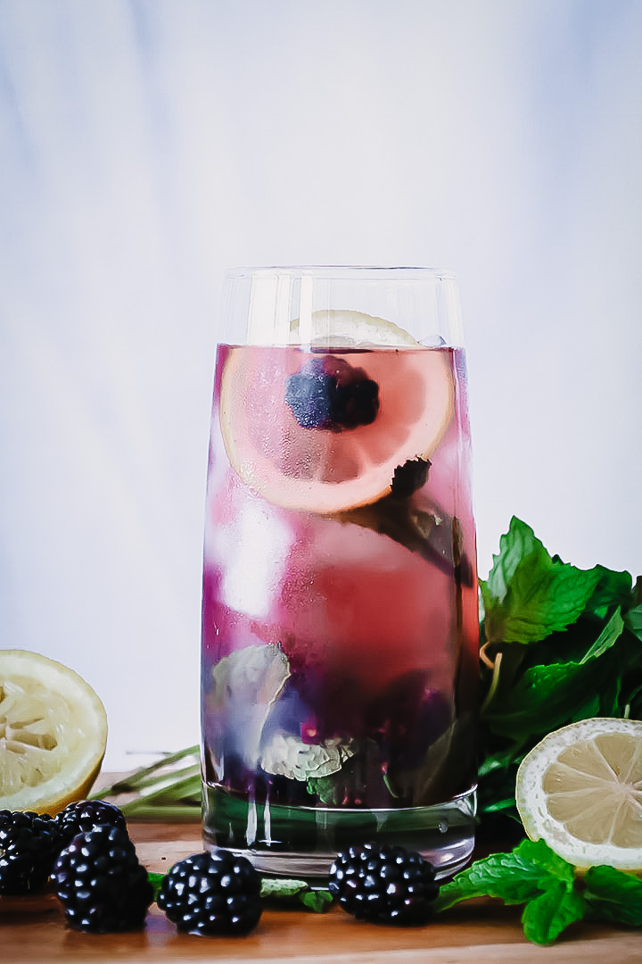 在一个切板的一杯煮的黑莓柠檬水用新鲜水果。