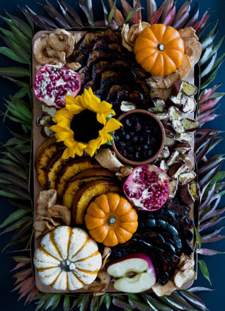 秋季收获小吃板，可挑剔的烤南瓜，橡子南瓜和秋季栗子，带有干苹果薯条，石榴和蔓越莓。