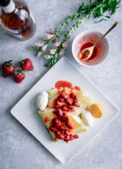 意大利乳清干酪和香草波旁草莓放在白色盘子里，蓝色的桌子上放着花。