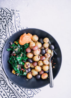 一个黑色的碗用早餐土豆，煮熟的绿色和大蒜aioli。