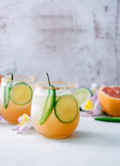 一杯玛格丽塔加葡萄柚、青柠、橙汁和辛辣的墨西哥胡椒，放在有鲜花的白色桌子上。