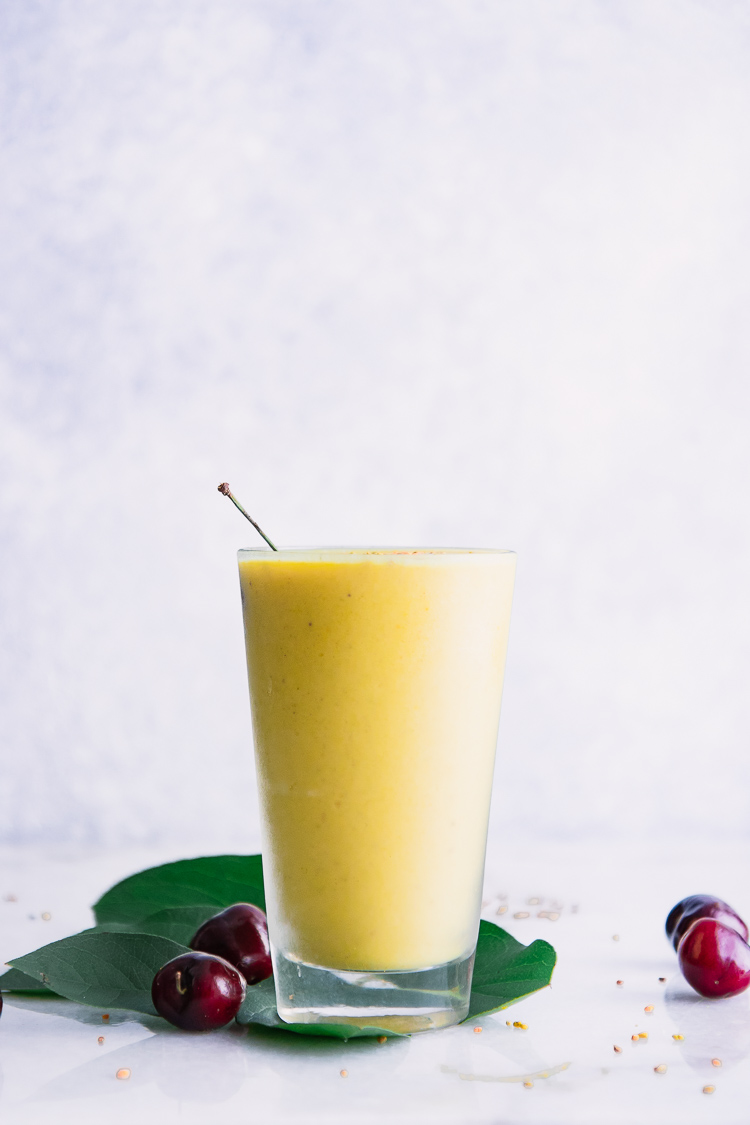 一张90度的照片，黄色芒果香蕉冰沙在一个玻璃与白色背景。