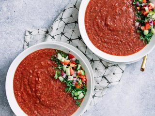 两个白色的碗，里面盛满了写着字样的红辣番茄西班牙凉菜汤