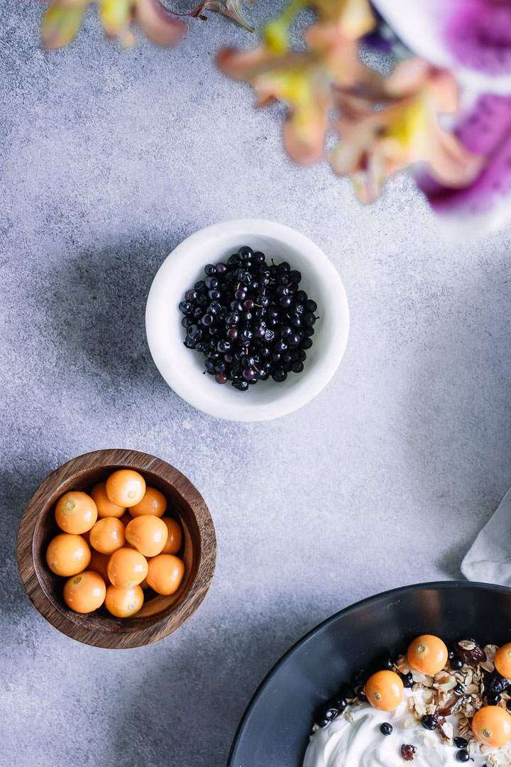 一小碗鹅莓和无核小葡萄干在一张蓝色桌上。