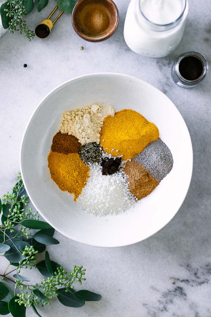 姜黄，生姜，椰子，肉桂，黑胡椒，肉豆蔻和小豆蔻放在一个白色的碗里。