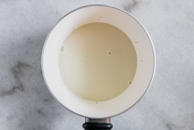 在白色大理石工作台上用小平底锅加热燕麦牛奶