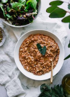 一碗在一张白色桌上的zuppa di farro汤与圣诞老人离开作为装饰和金匙子和白色餐巾