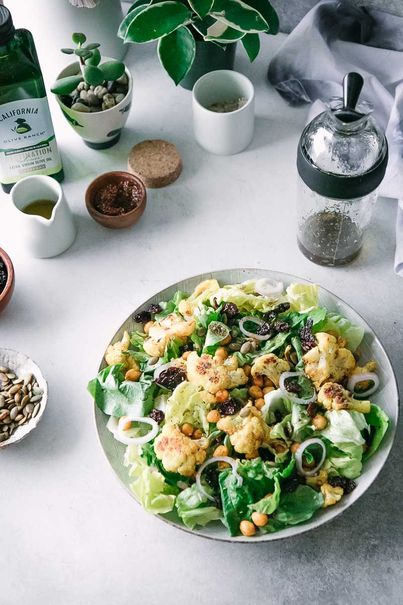 沙拉用花椰菜和鸡豆在一张白色桌上与小碗和茶碟拿着香料和油