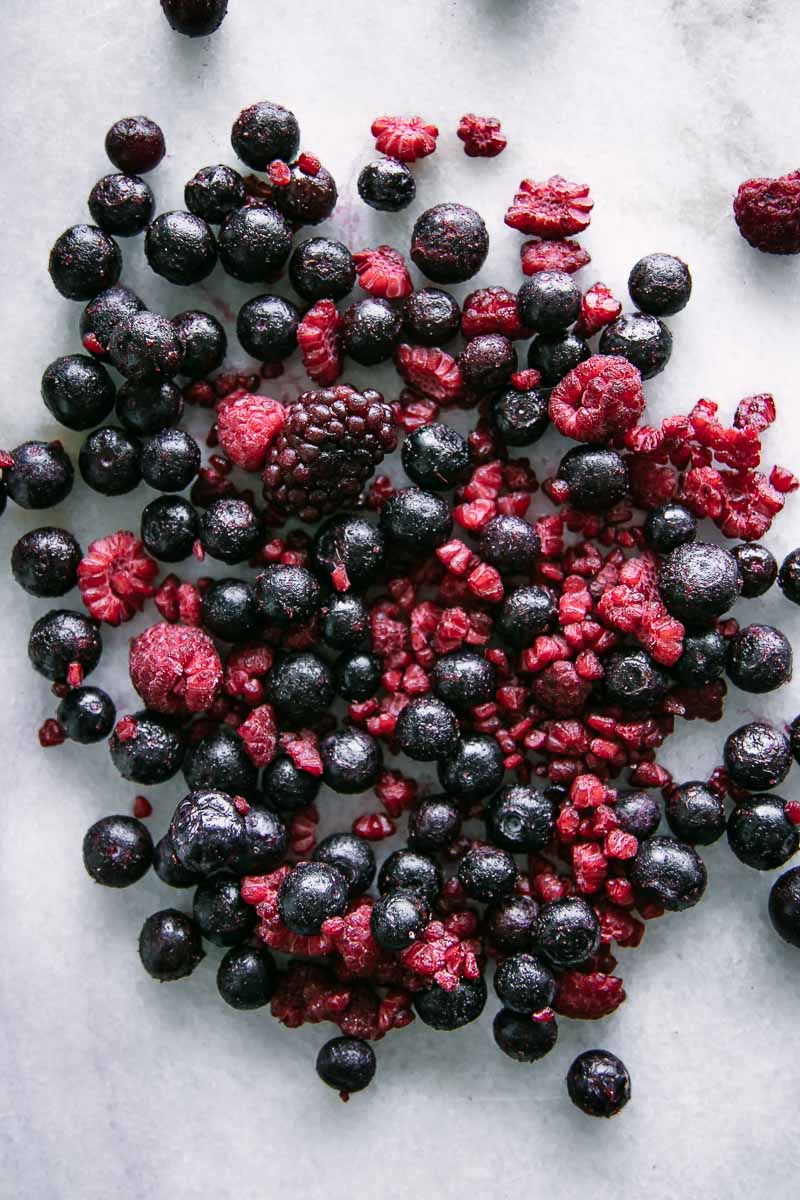 白色的桌子上放着冰冻的黑莓、蓝莓和覆盆子