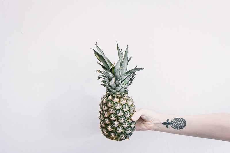 一只手的水平的比率照片有拿着菠萝的菠萝纹身花刺有白色背景