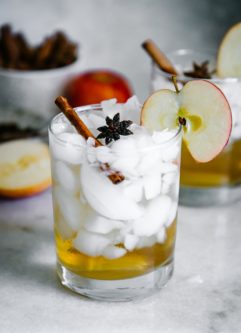 一杯加冰、苹果醋和苏打水，配上一块苹果片，放在白色的桌子上