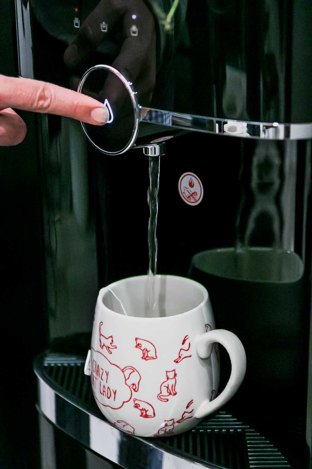 用手指把水从高档饮水机里倒进咖啡杯里