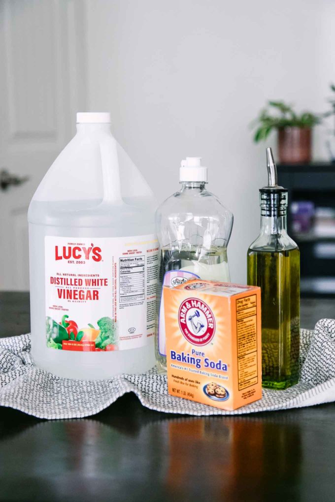 瓶蒸馏的白色醋，洗碗肥皂，油和小苏打在一张木桌上