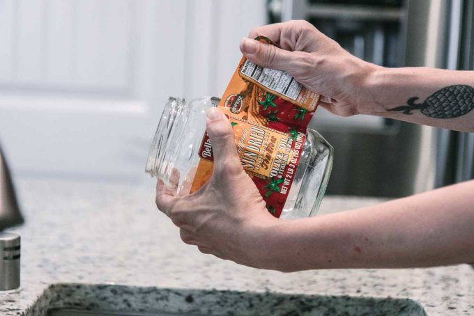 一只手从一个空的玻璃食品罐上撕下标签