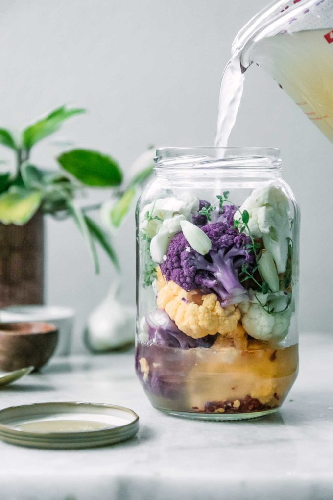 一罐白色、紫色和黄色的花椰菜，并倒入醋盐水