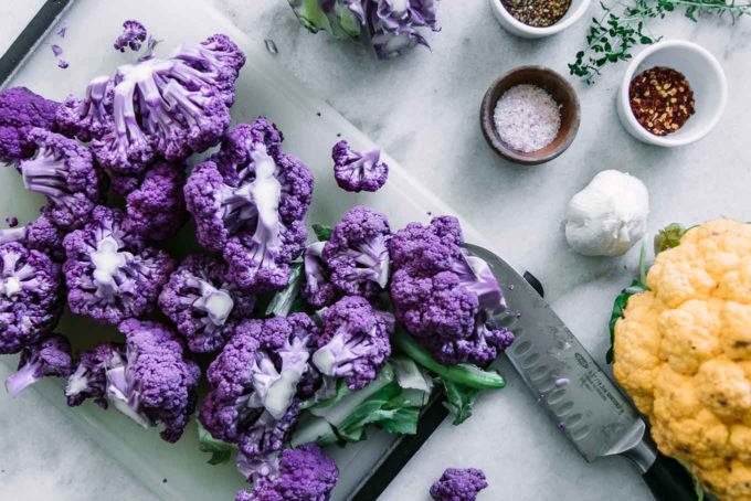 用刀在砧板上切紫色的花椰菜