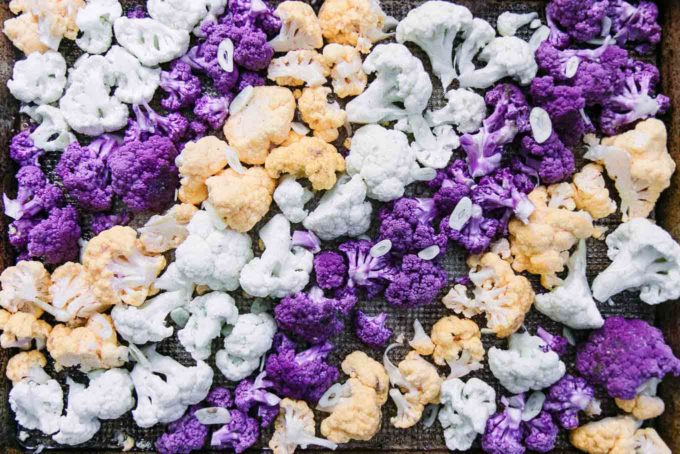 白色、紫色和橙色的花椰菜在烤盘上排成五颜六色的线
