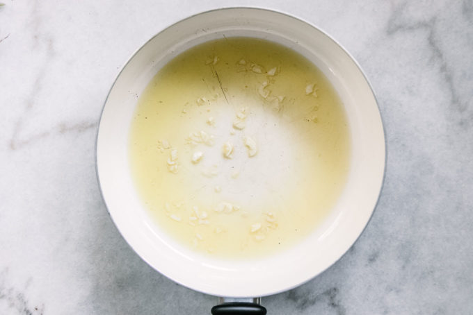 橄榄油和切的大蒜在一张白色平底锅的在一张白色桌上