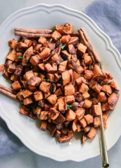 baked sweet potatoes on a white plate with cinnamon sticks