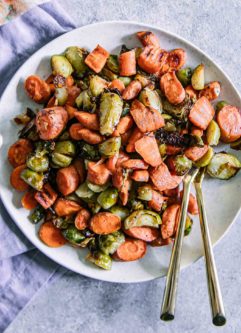 roasted brussels sprouts and carrots on a white plate with a gold fork