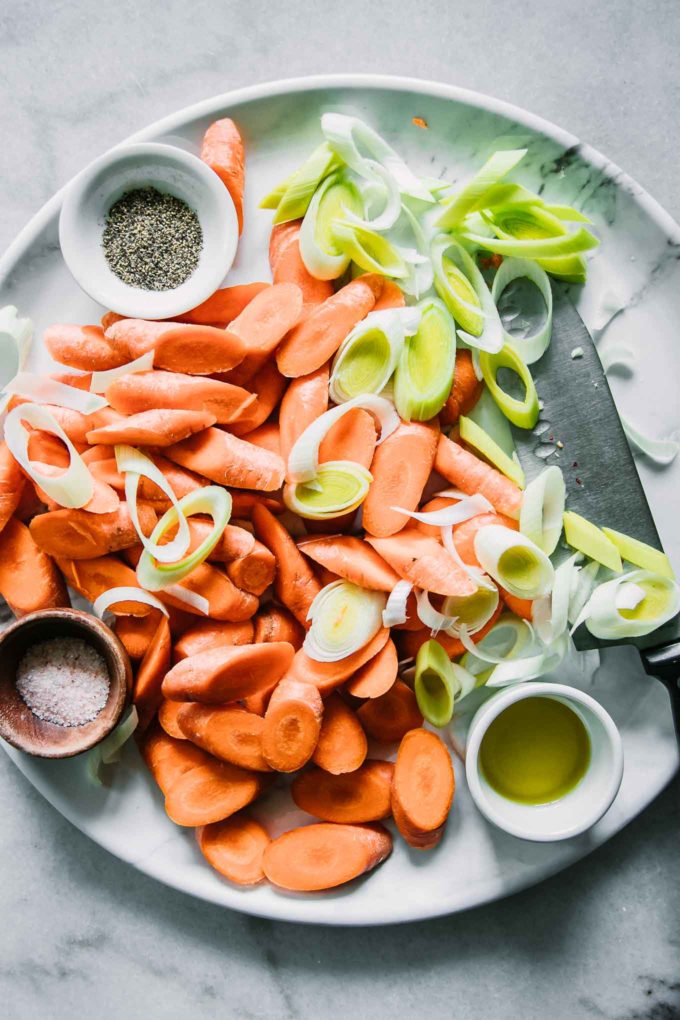 将胡萝卜和韭菜切成小块，放在白色的盘子里，盛上油、盐和胡椒粉