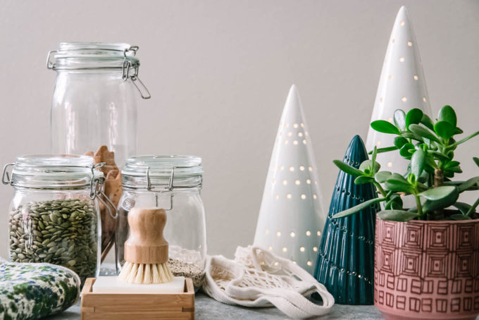可重复使用的洗碗刷，玻璃食品储存罐和可重复使用的购物袋在桌子上与假日树装饰