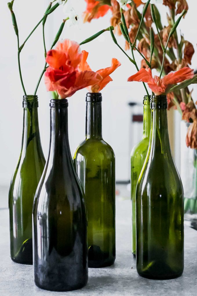 白色的桌子上放着酒瓶、花瓶和橙色的花