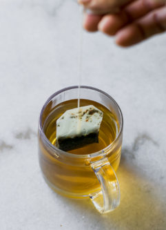 一只手拉出茶袋的咖啡杯咖啡杯