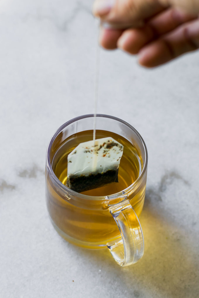 一只手拉出茶袋的咖啡杯咖啡杯