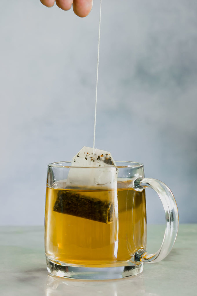 一只手拉出茶袋的玻璃茶杯