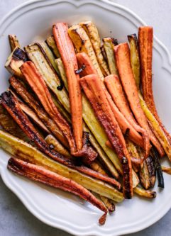 roasted carrot and parsnips on a white plate on a white table