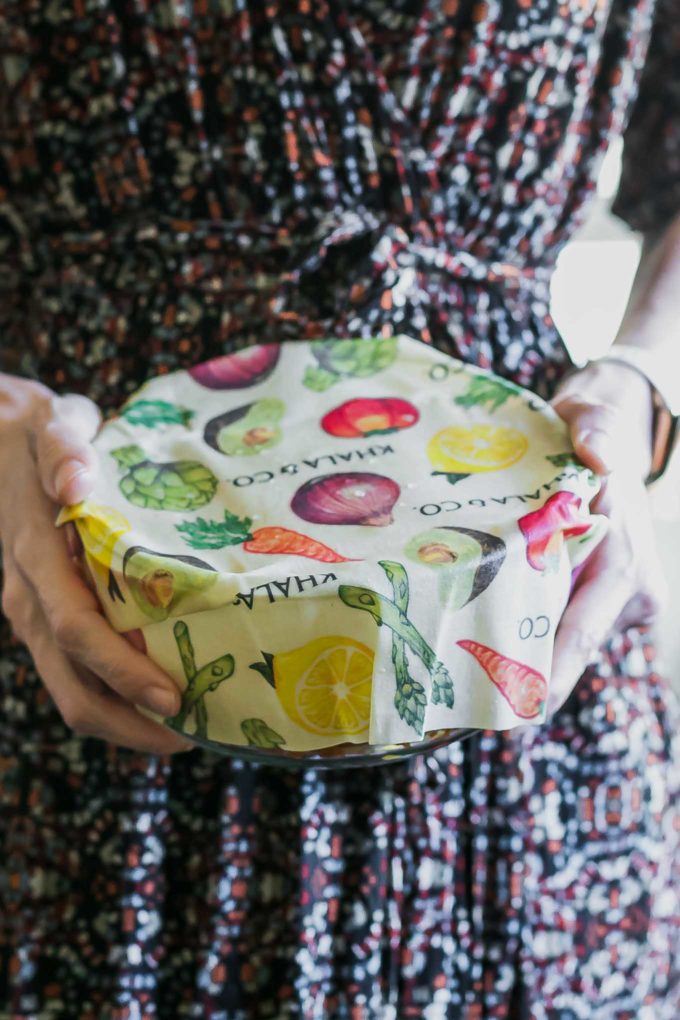 a woman holding a bowl covered with beeswax wrap