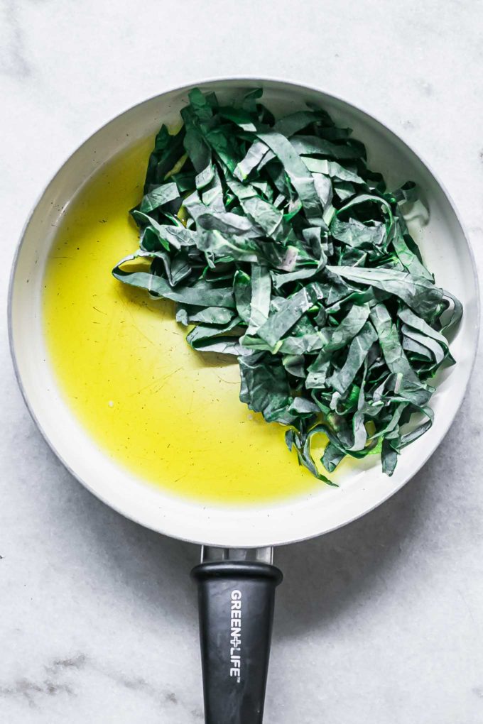 橄榄油和切片的布鲁塞尔豆芽在白色的平底锅中露出绿色GydF4y2Ba