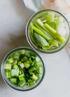 切成薄片和切成腌制的绿色洋葱在玻璃罐中