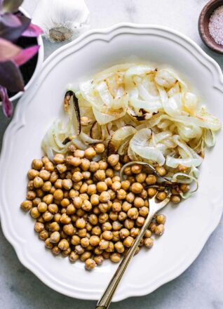 烤鹰嘴豆和洋葱放在白色盘子里，用金叉子