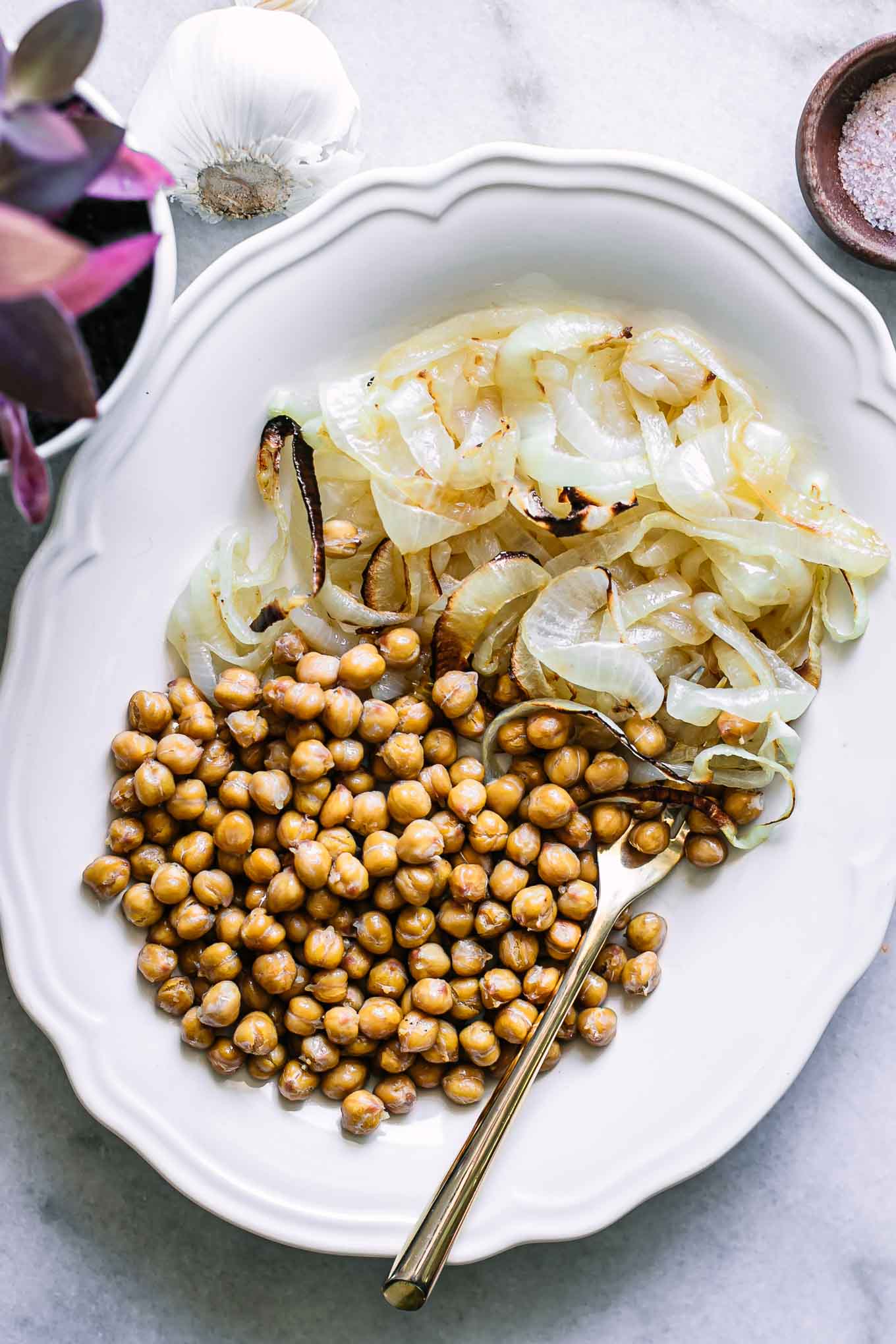 烤鹰嘴豆和洋葱放在白色盘子里，用金叉子gydF4y2Ba